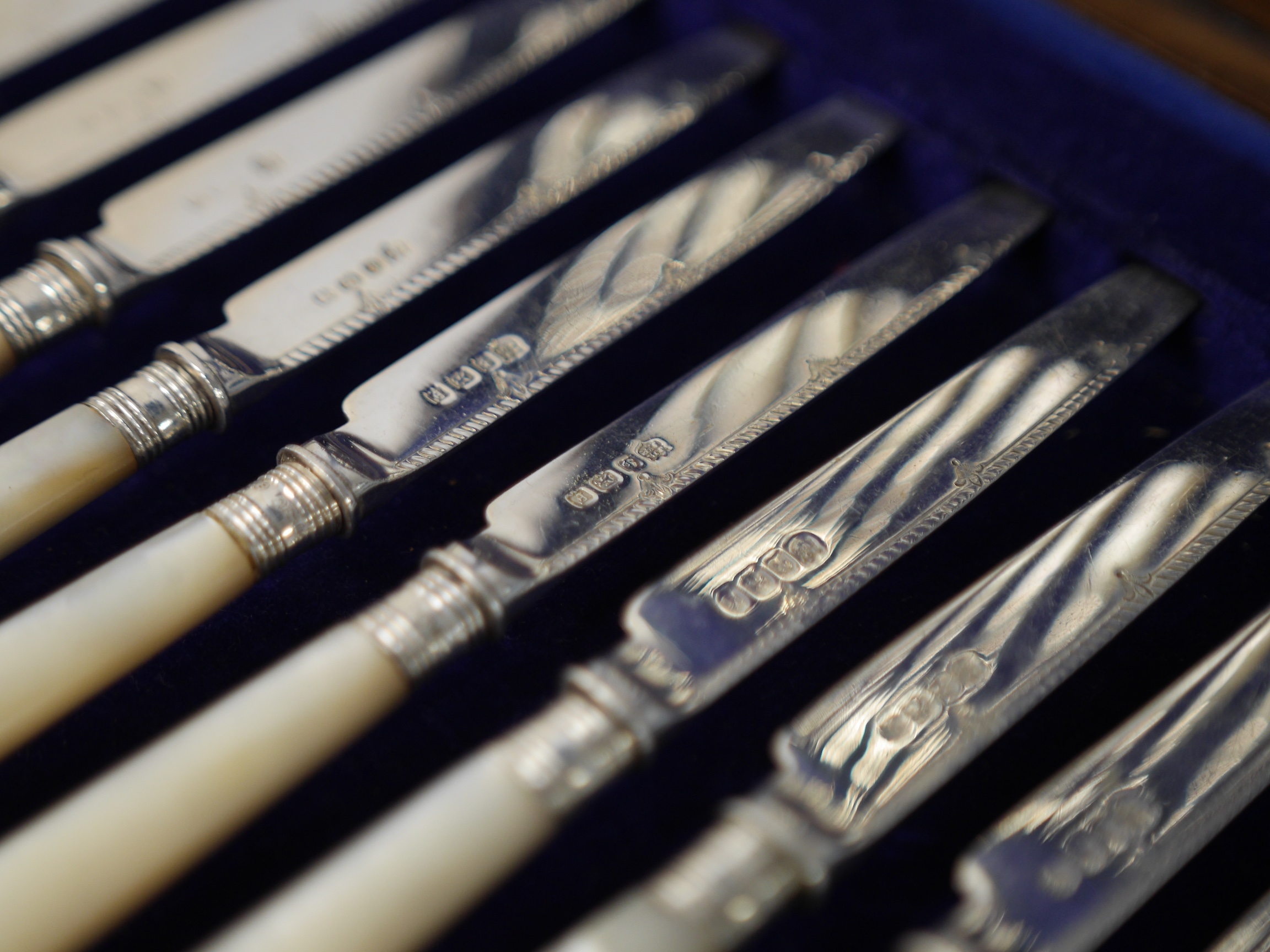 Twelve George V mother of pearl handled silver dessert eaters and eleven matching dessert forks, Barker Brothers Silver Ltd, Birmingham, 1930, knife 18.5cm, housed in a fitted mahogany canteen. Condition - fair to good